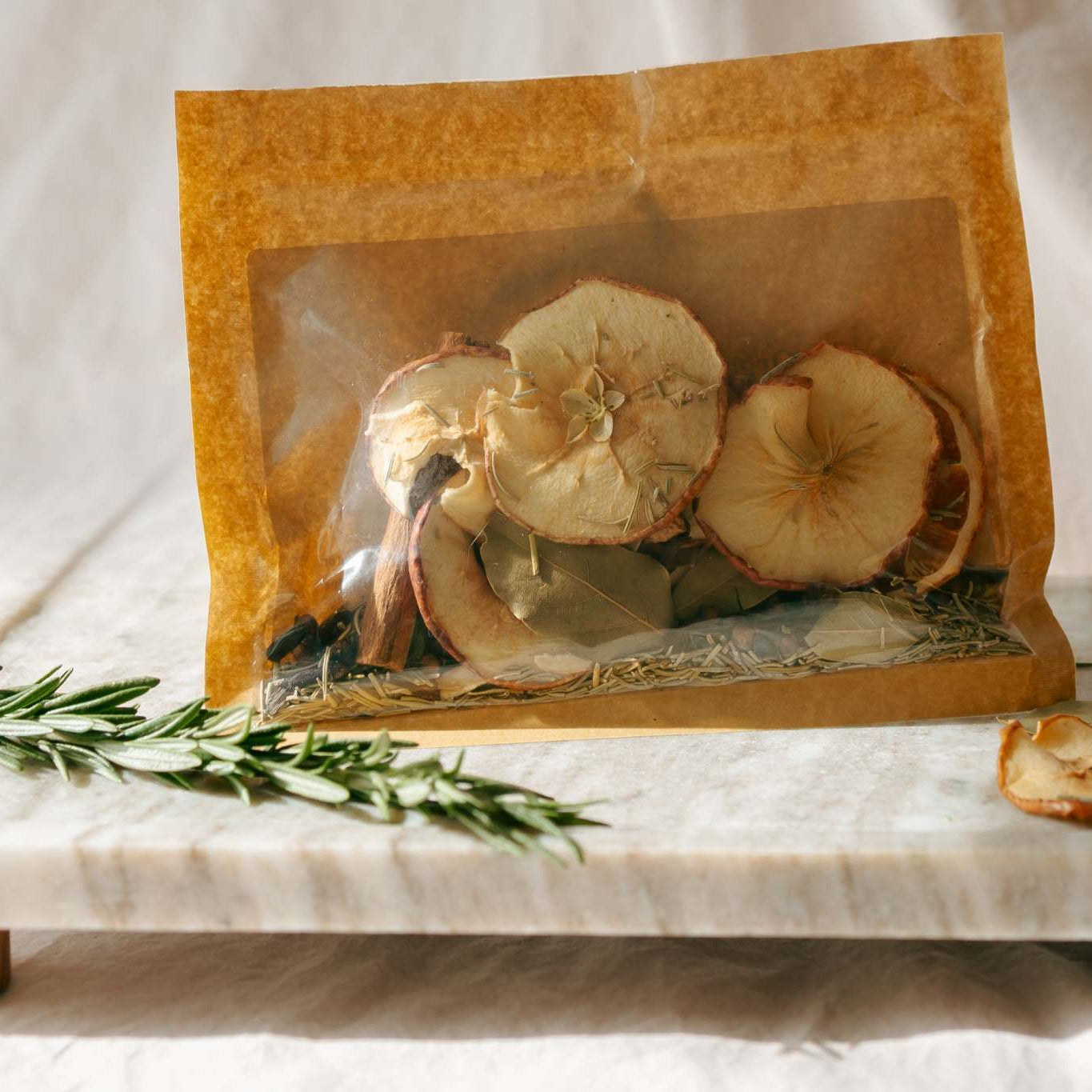 Dried apples in a clear bag on a marble surface with a white background