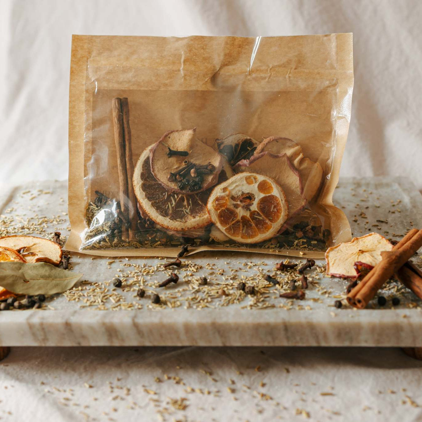 Spice blend with oranges, cinnamon sticks, and cardamom pods on a marble tray.