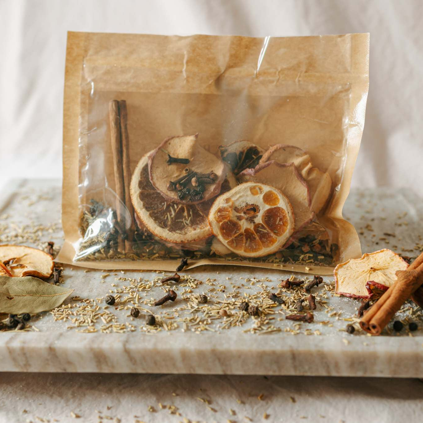 Spices and dried oranges on a marble slab with a clear bag in the background