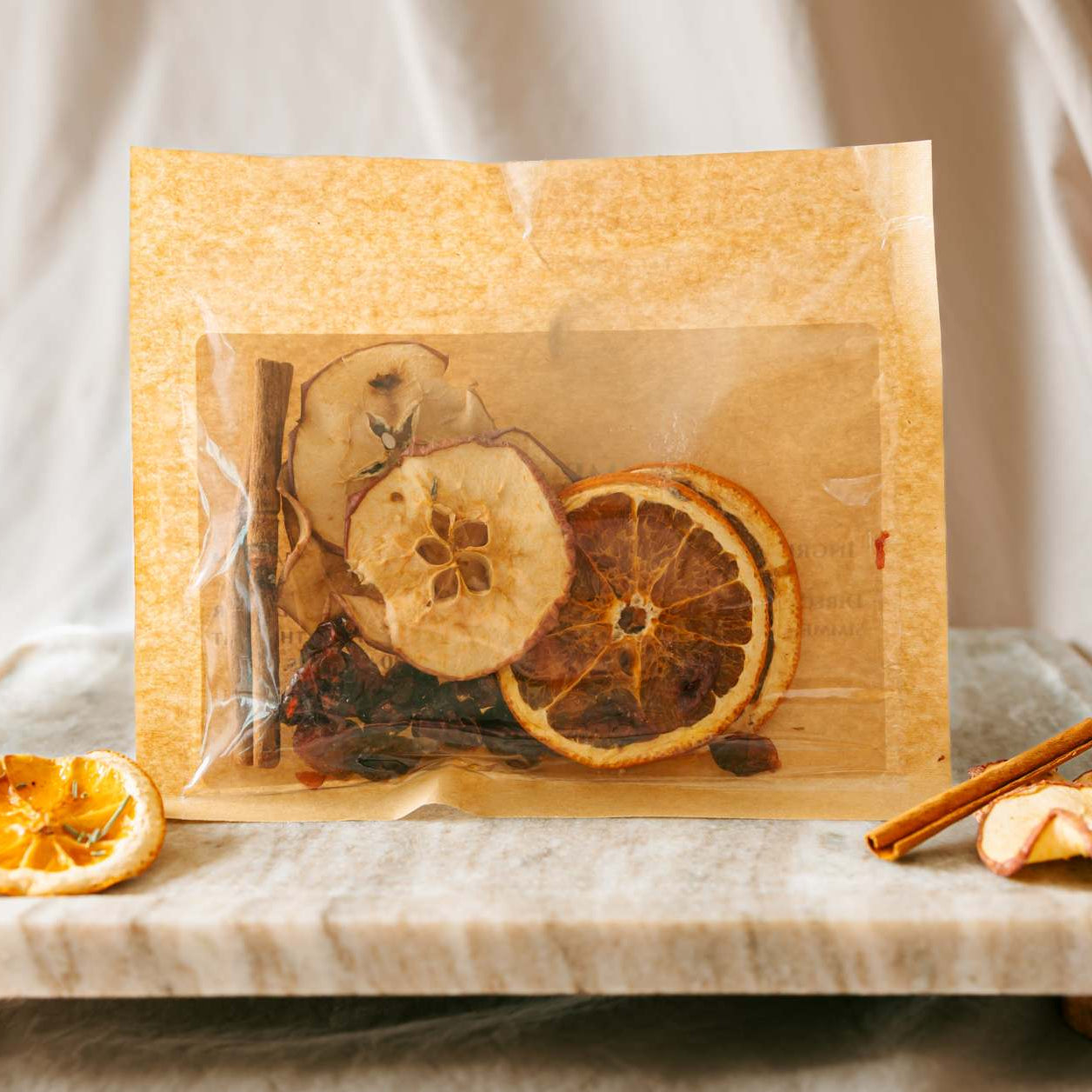 Dried fruits and spices in a clear bag on a wooden board with a neutral background