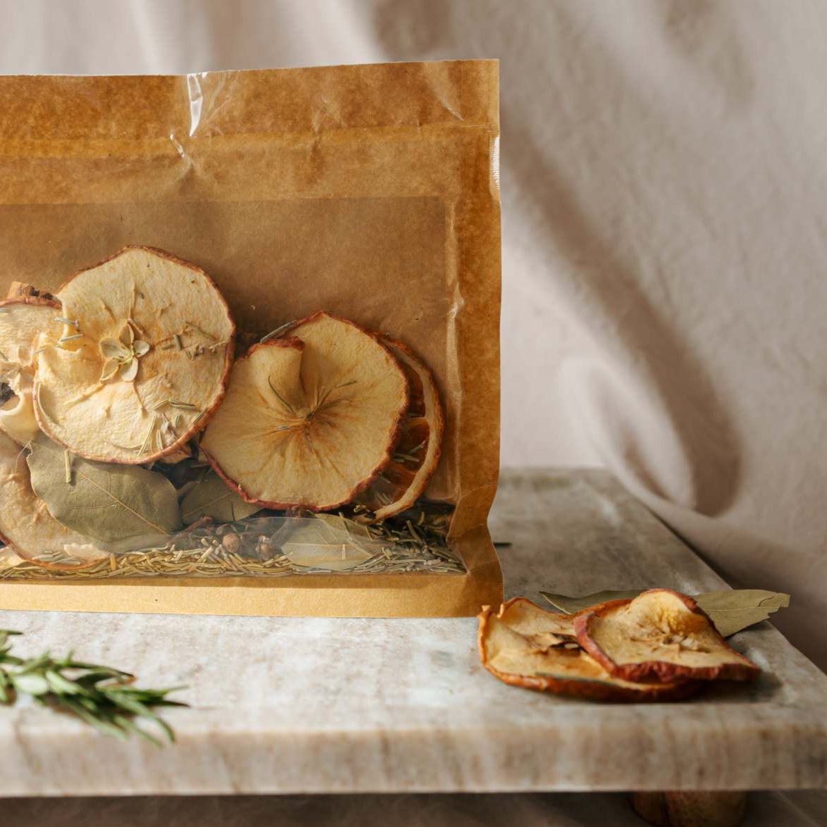 Dried apples in a clear bag on a marble surface with a light background