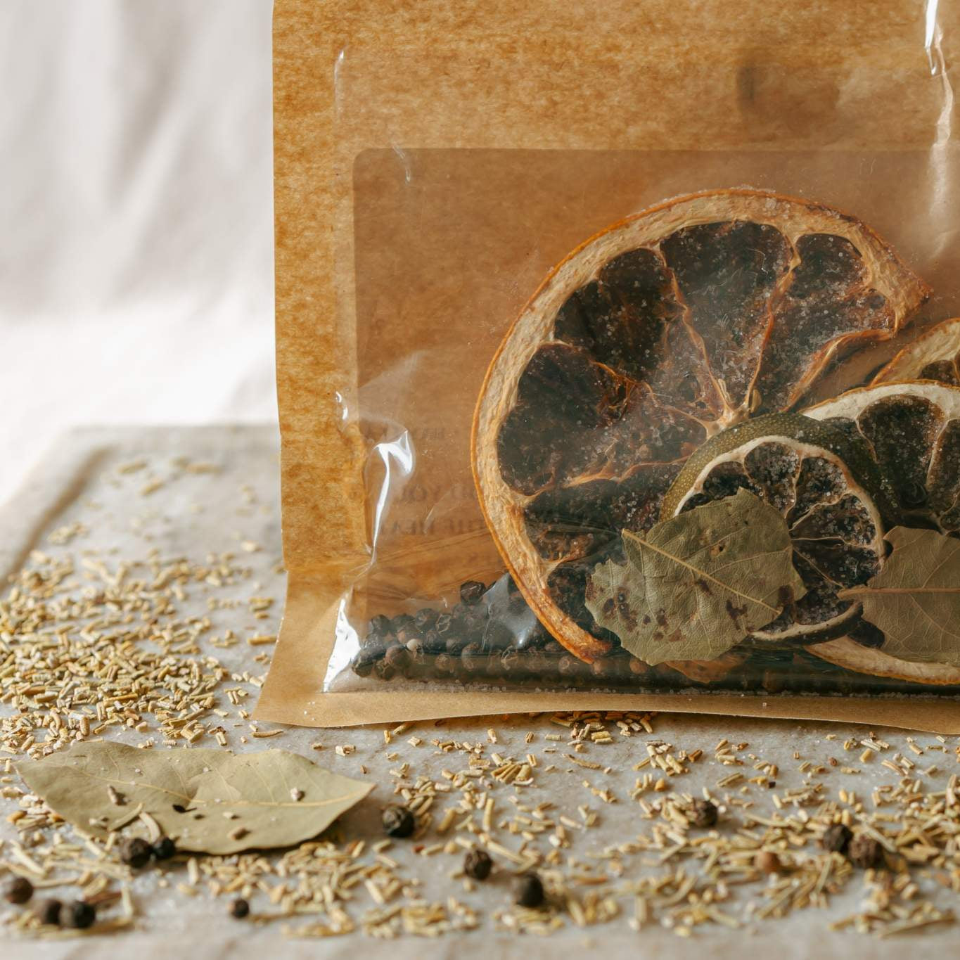 Dried citrus slices and herbs in a clear plastic bag on a textured surface.