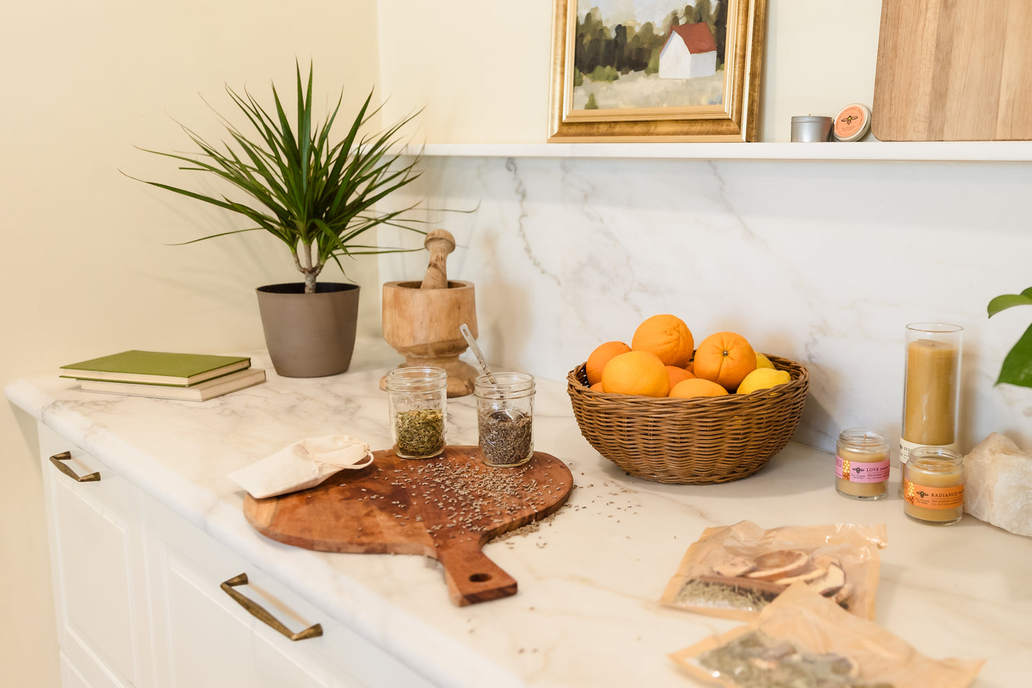 Kitchen counter with a cutting board, basket of oranges, and various items on a marble countertop.