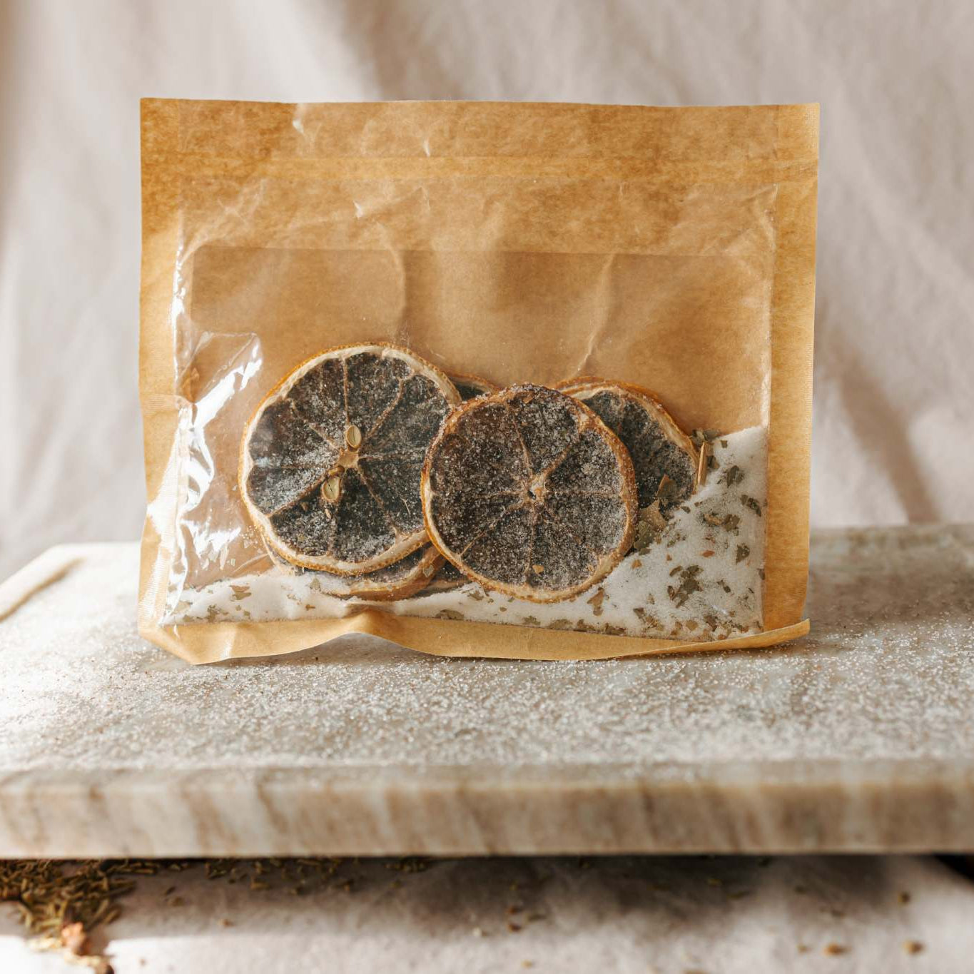 Dried herbs in a brown paper bag on a marble surface with a neutral background