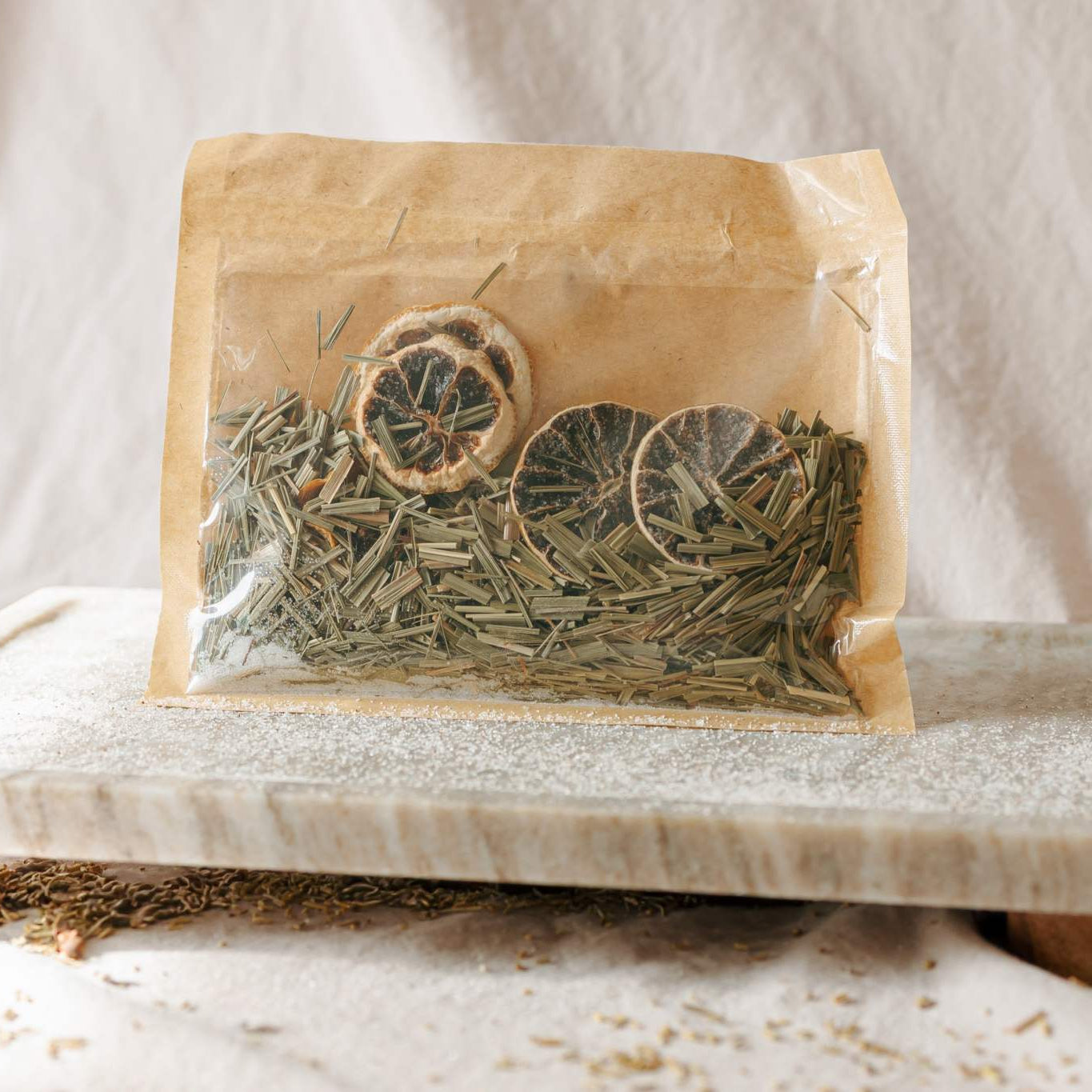 Herbal package with dried herbs on a marble slab against a neutral background