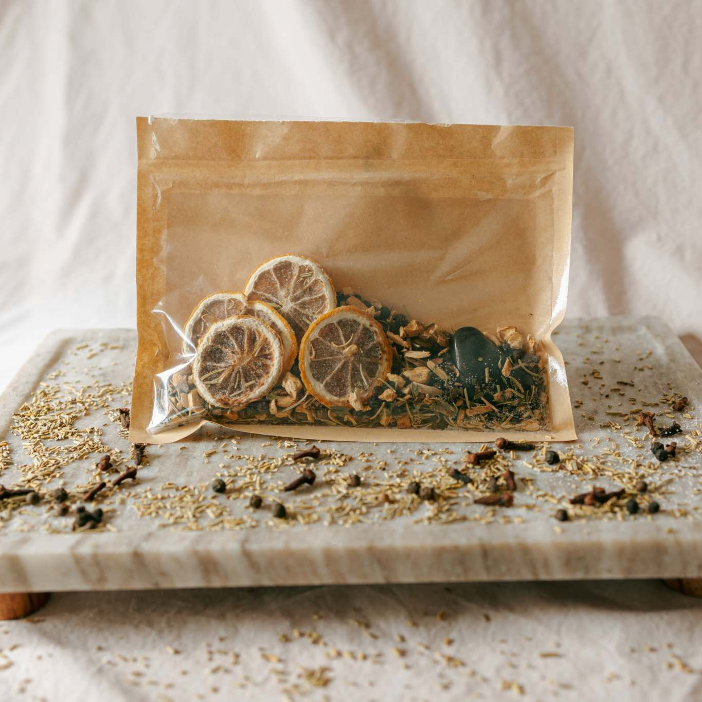 Simmer pot packaging with lemon slices on a marble tray against a white background